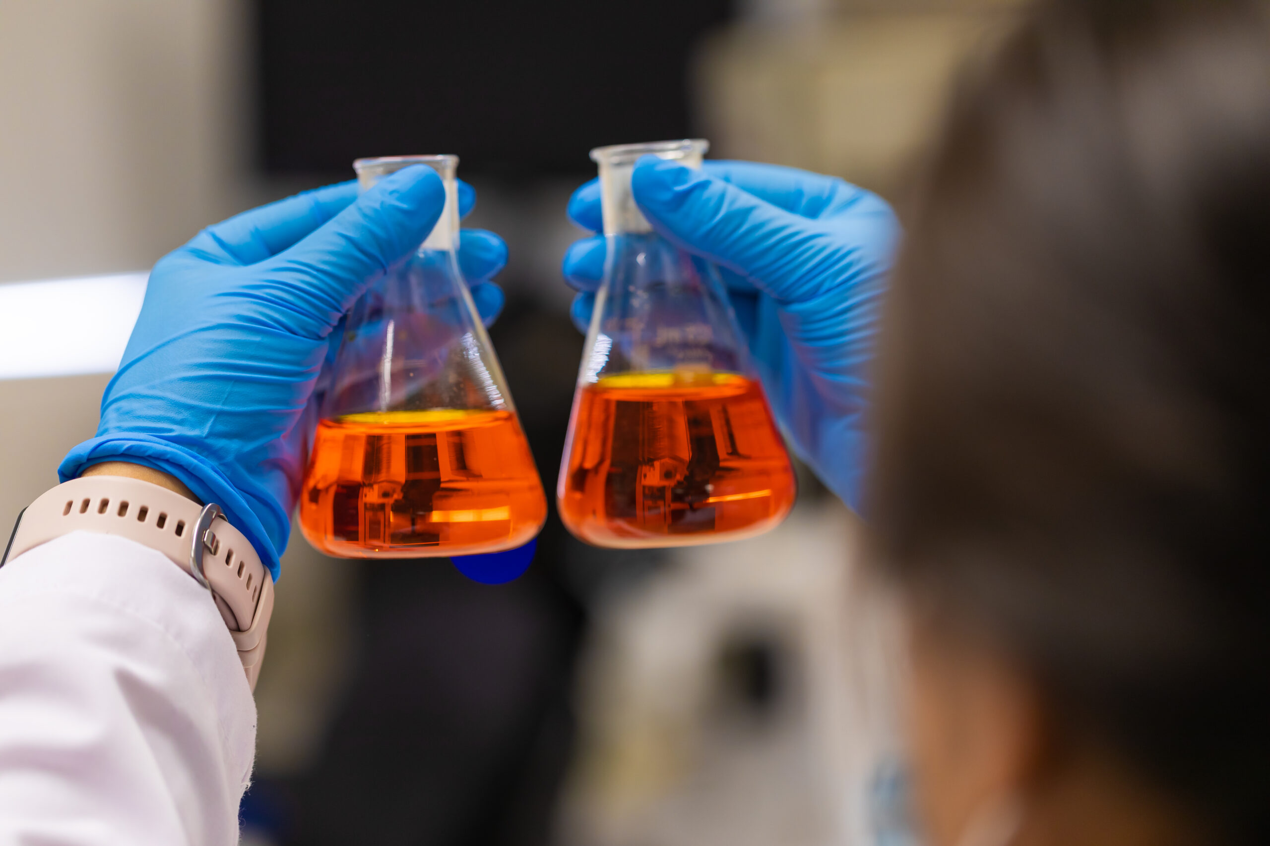 Analista de laboratorio realizando un análisis químico en un laboratorio, utilizando equipo de protección. Esta imagen ilustra la importancia de la seguridad y el cuidado en el manejo de sustancias químicas en un entorno de laboratorio, así como la profesionalidad y el compromiso del analista con su trabajo